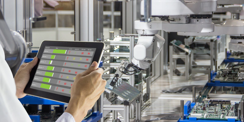 a high tech manufacturing facility with an operative holding a tablet device in the foreground