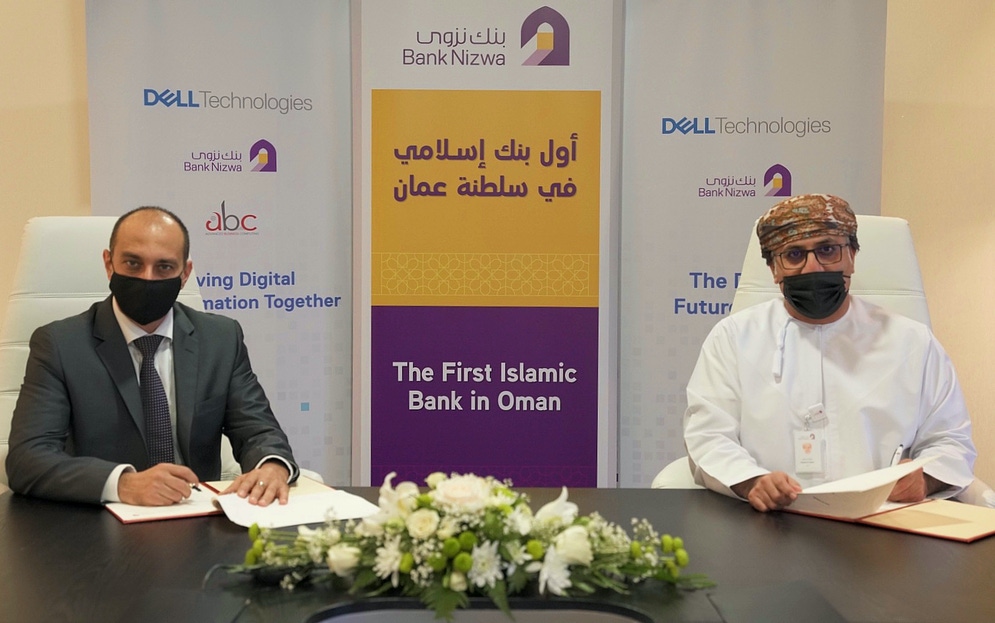 two men are seen sitting at a table signing documents