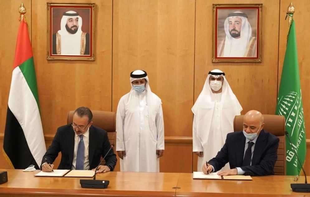 shows two men sitting at desks signing an agreement.