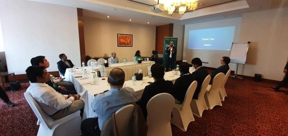 peopple are seen sitting around a boardroom table watching a presentation