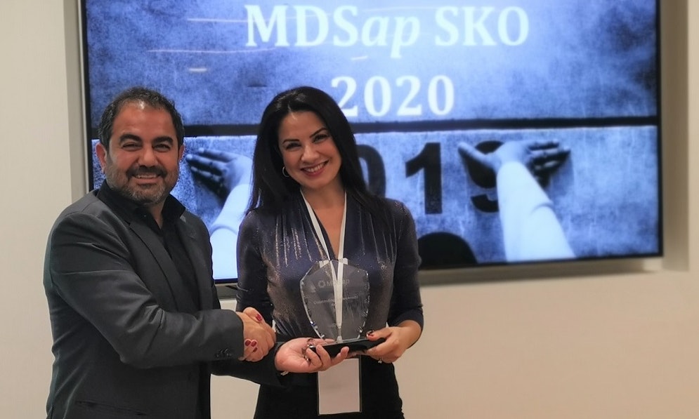 A man in a business suit presents a woman with a glass trophy