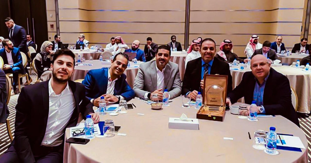 a group of people are seen at a table watching a presentation