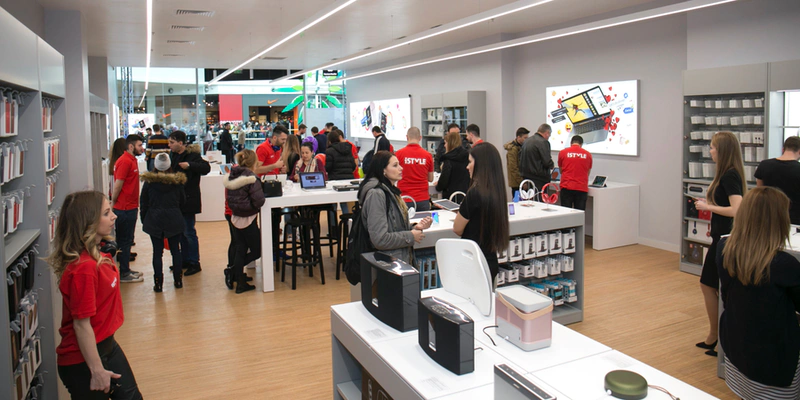 shows the interior of a hi-tech retail shop with sales people wearing red t-shirts