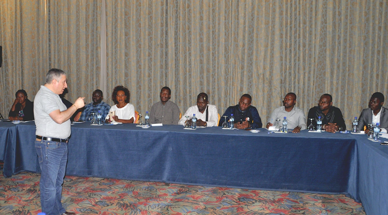 a man is seen presenting to a group of people sitting at tables