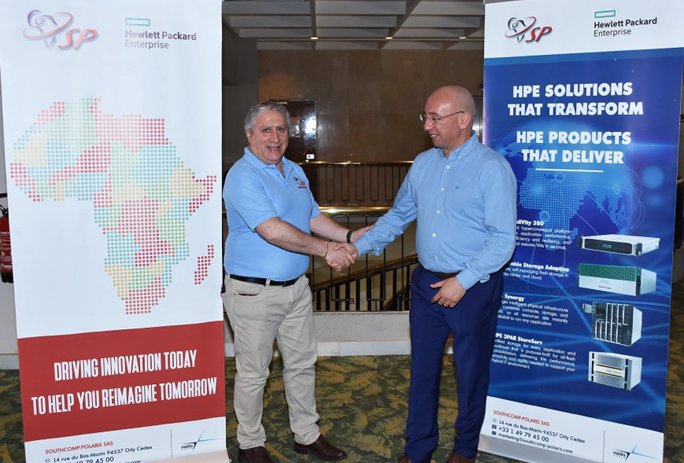 Two men are seen shaking hands between two display placards