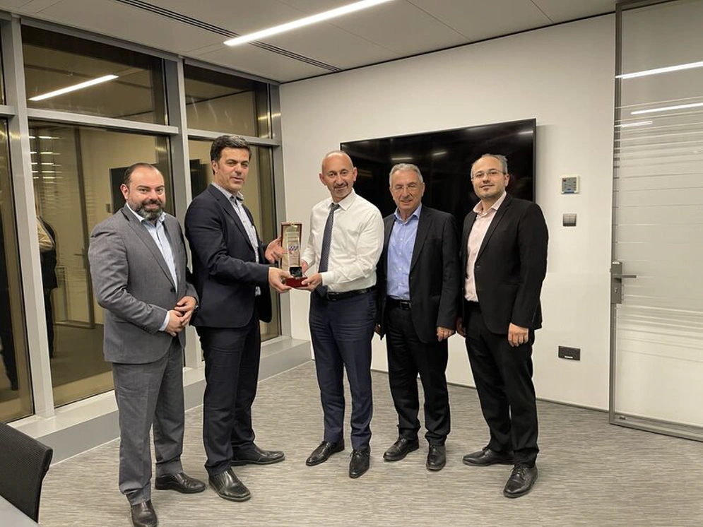 five men in suits are seen with a trophy being handed over