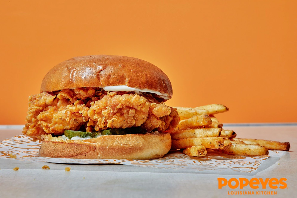 shows a chicken sandwich with a popeyes logo