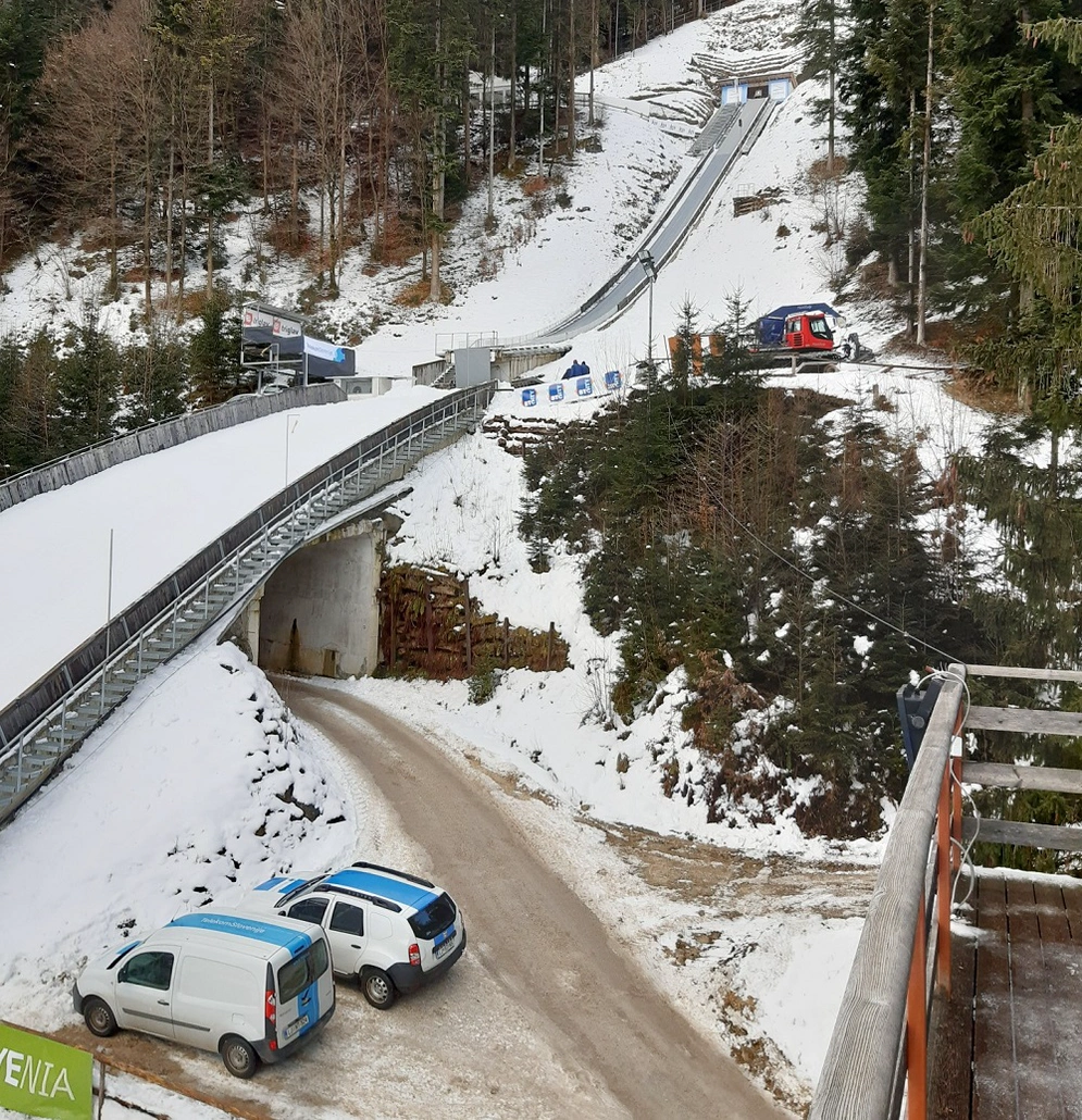shows a snow-covered ski-jump with vehicles in the foreground