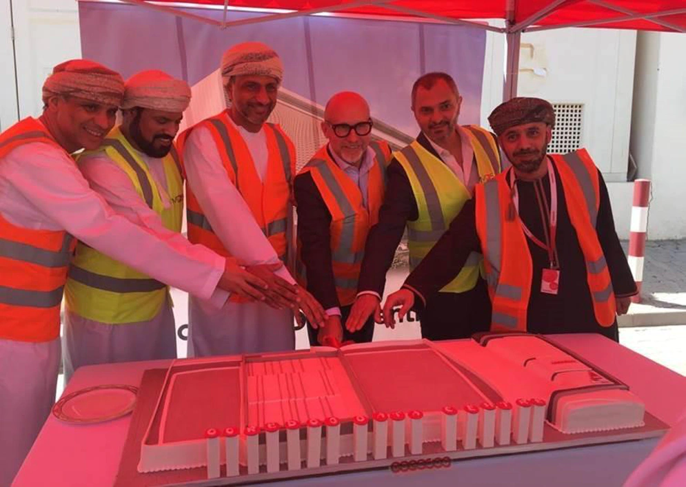 six men are seen side by side as one of them cuts a celebration cake