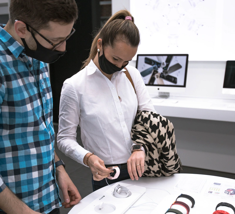 two people are looking at digital devices on a plinth