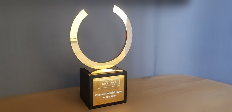 a gold and black coloured trophy is seen on a desk with the words commercial distributor of the year engraved on it