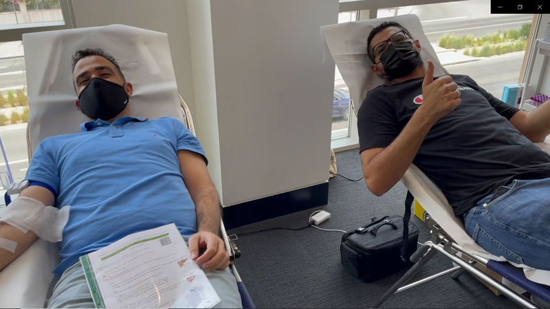 two men recline side by side to give blood