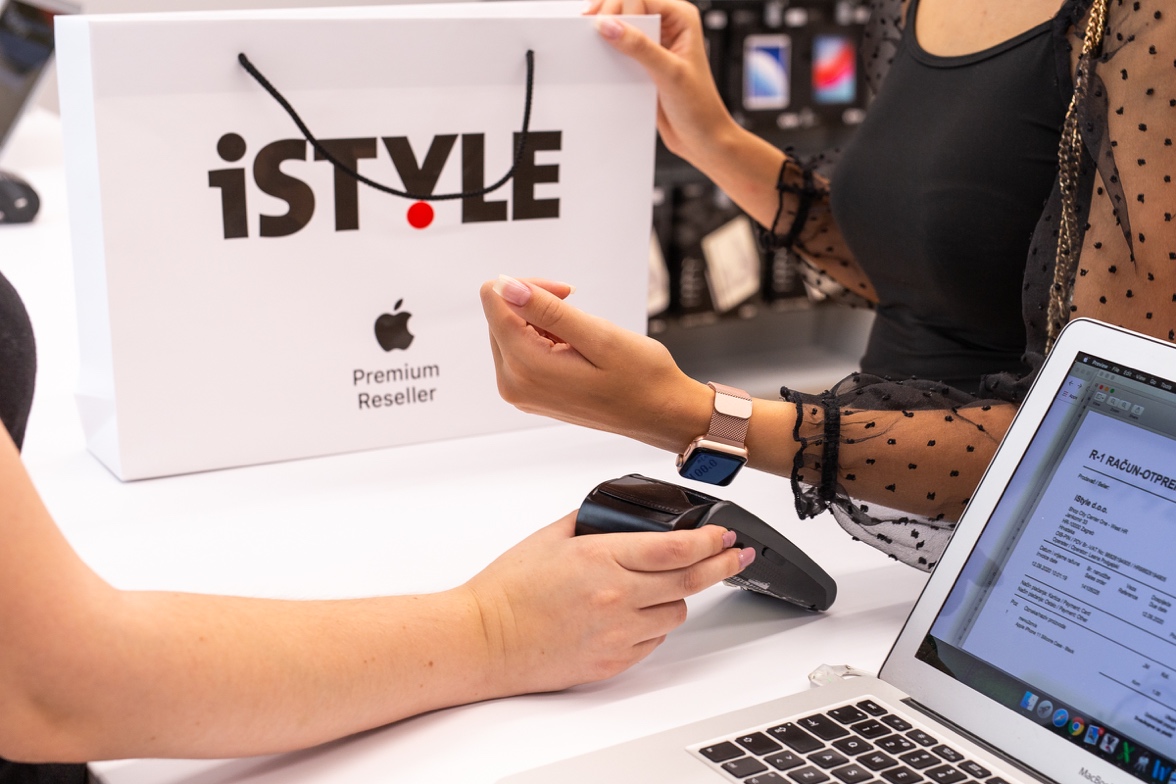 two people reach across a retail counter with one holding a credit card payment device