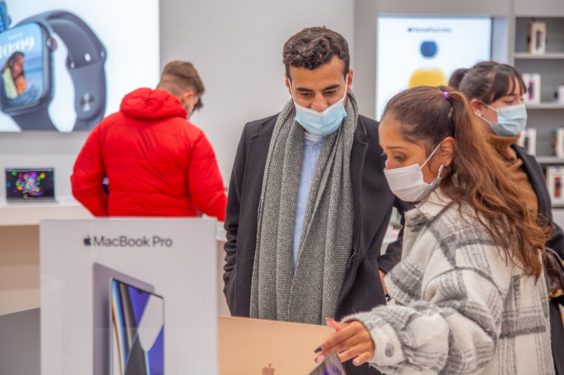 two people are seen looking at Apple devices