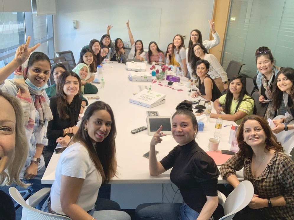 Group photo of a large team of women all sitting around a table