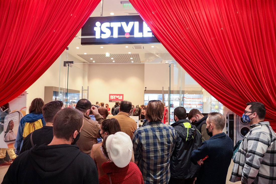 a crowd of people wait around the door of a hi-tech store