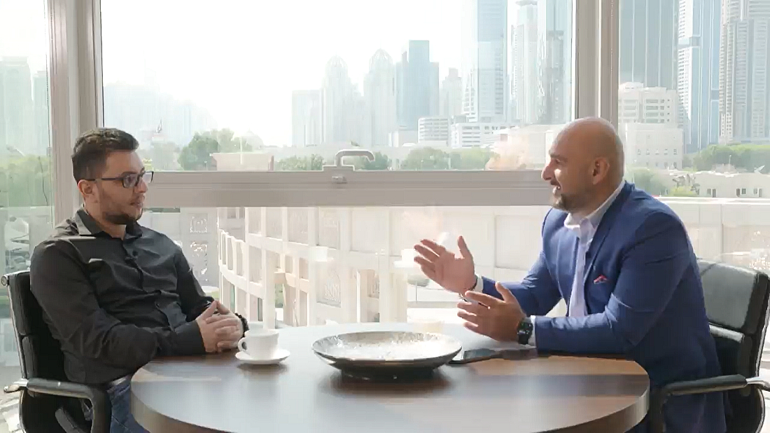 two men seen sitting at a table in discussion