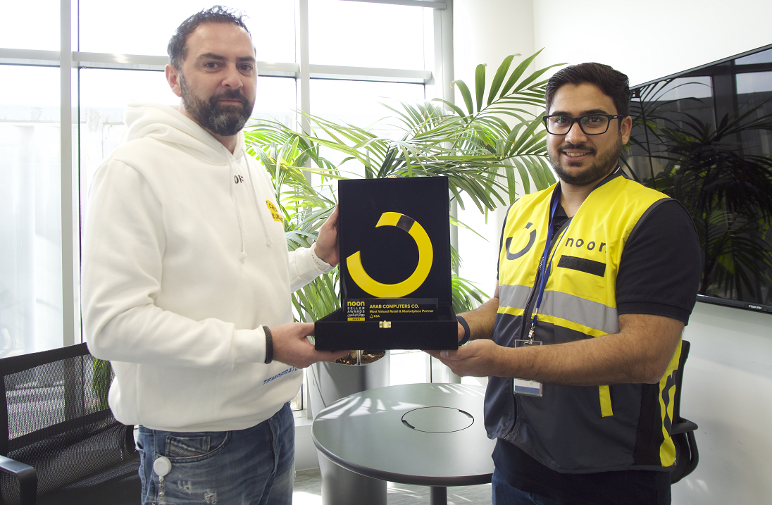 two men are seen with a black and yellow coloured award