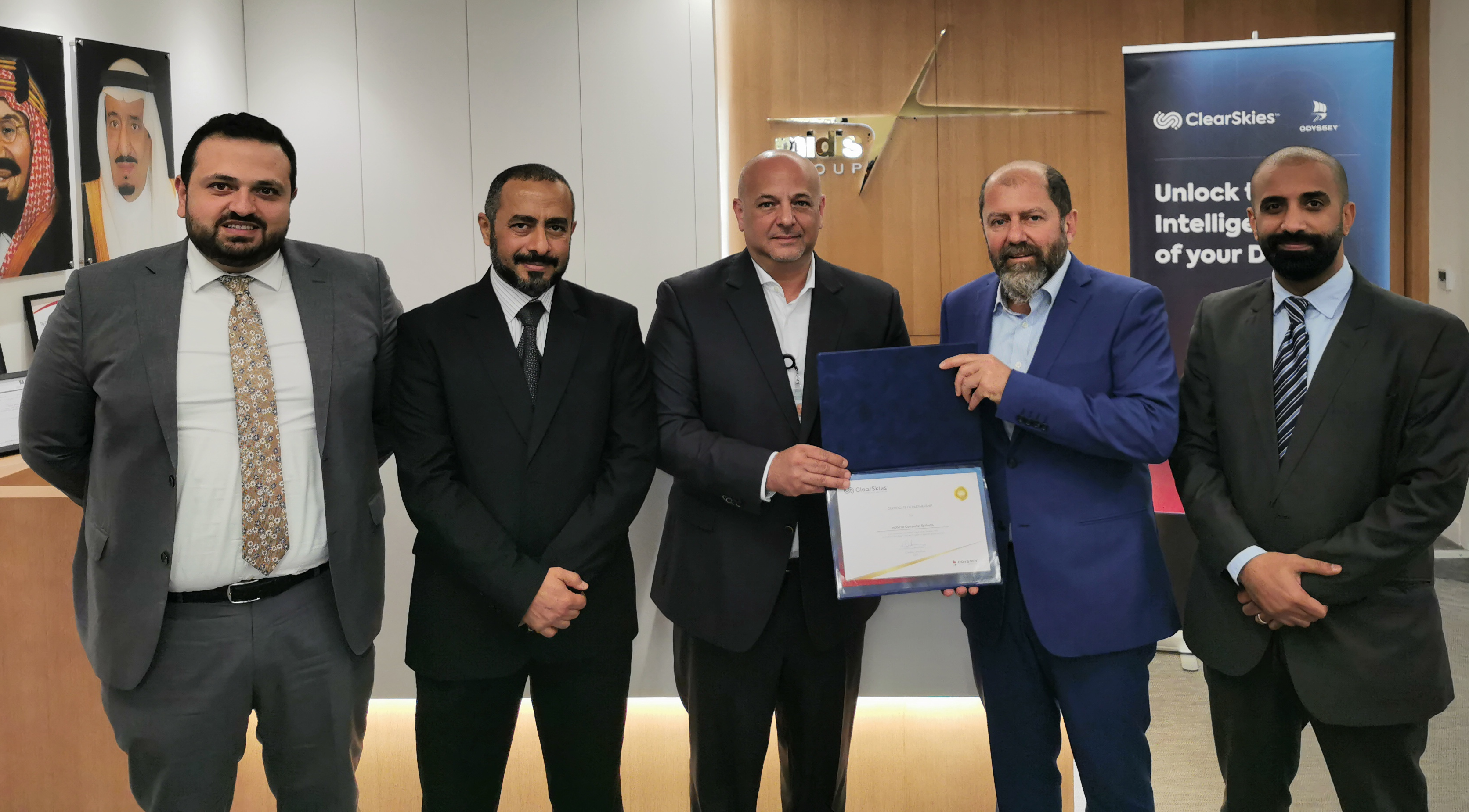 five men seen together in an office as one of them presents a certificate