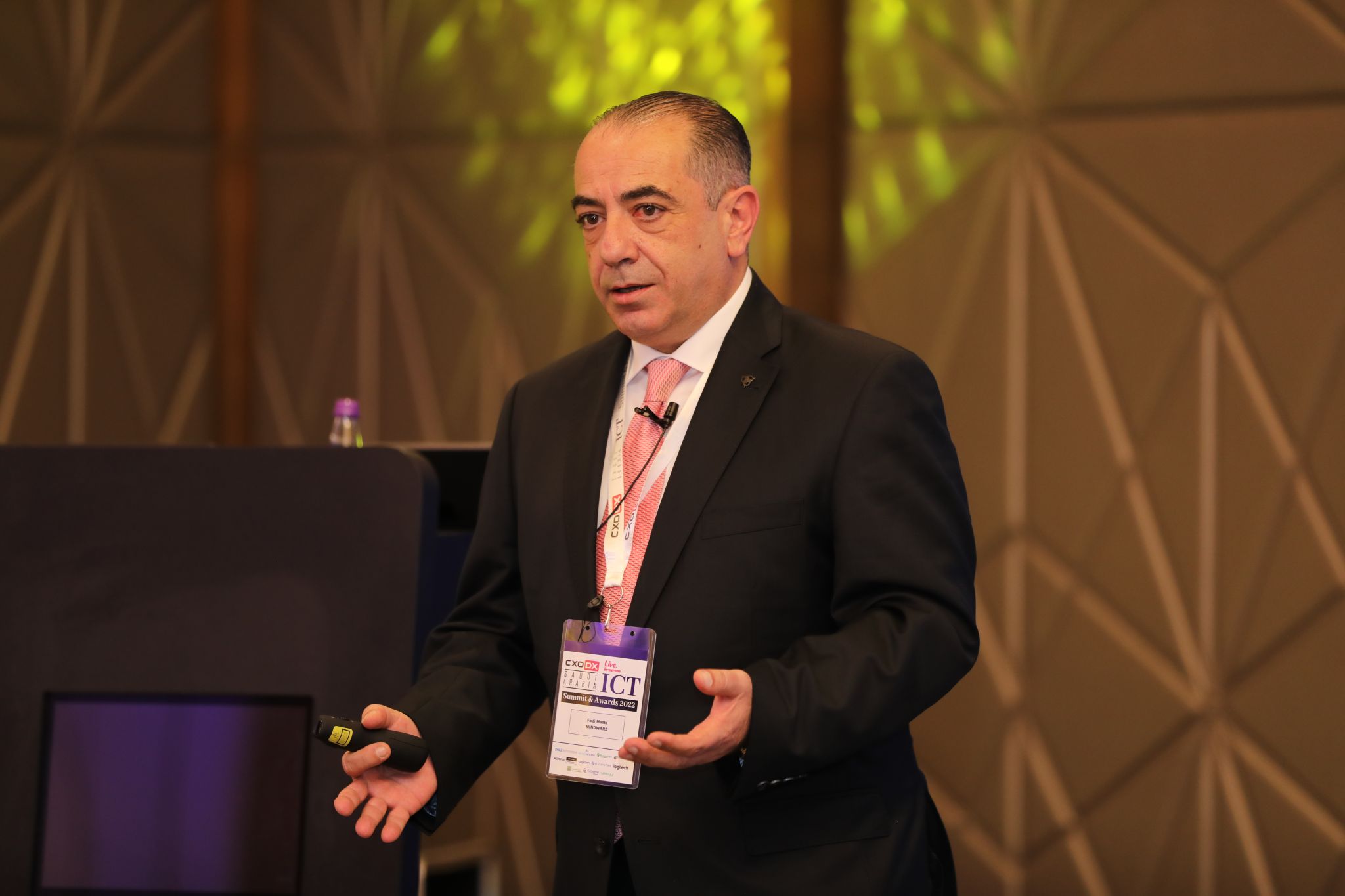 a man in a suit and tie is speaking on a conference stage