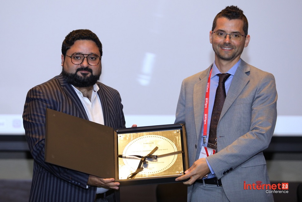 two men in suits are seen, one is handing an award to the other. 