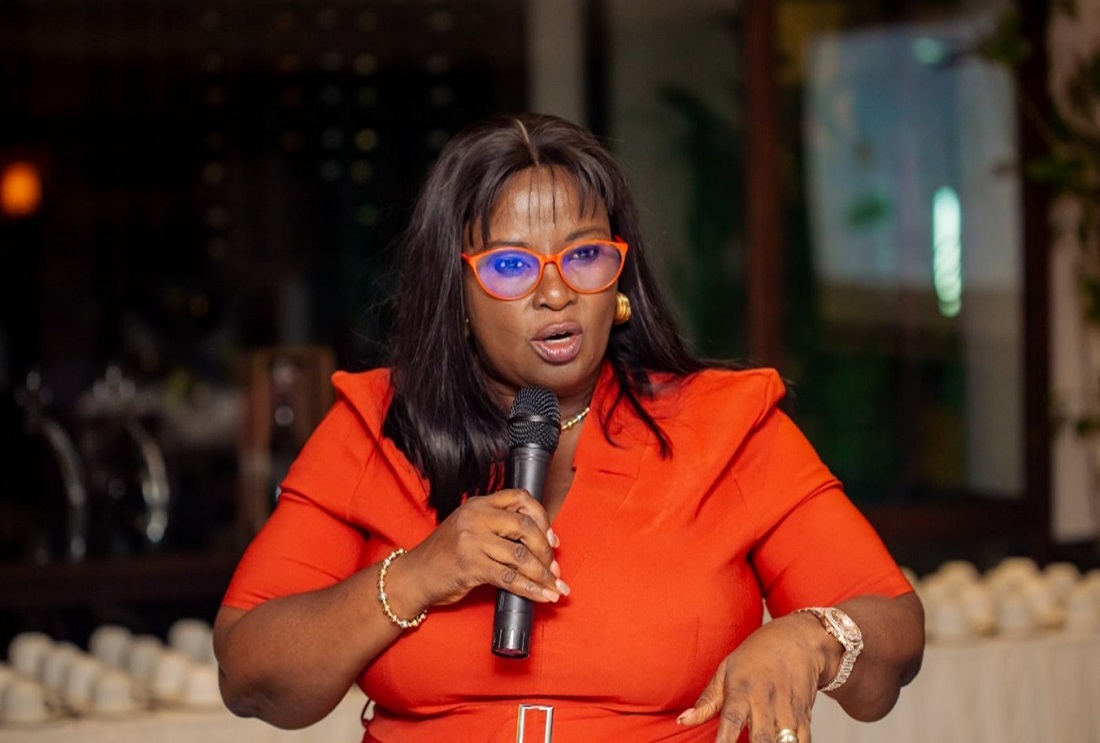 a woman in an orange business suit is talking with a microphone