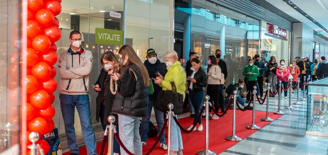 a large queue of people outside a hi tech store