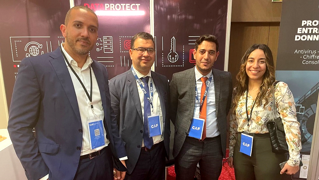 three men and one woman stand together wearing lanyards at an event