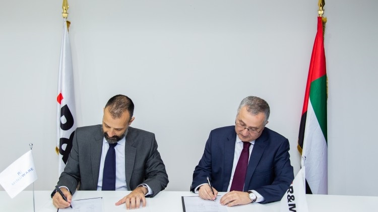 two men sit at a table signing agreements