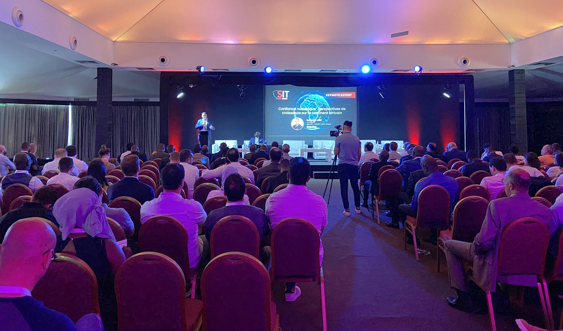 a room full of people sitting in rows watching a presentation from a stage