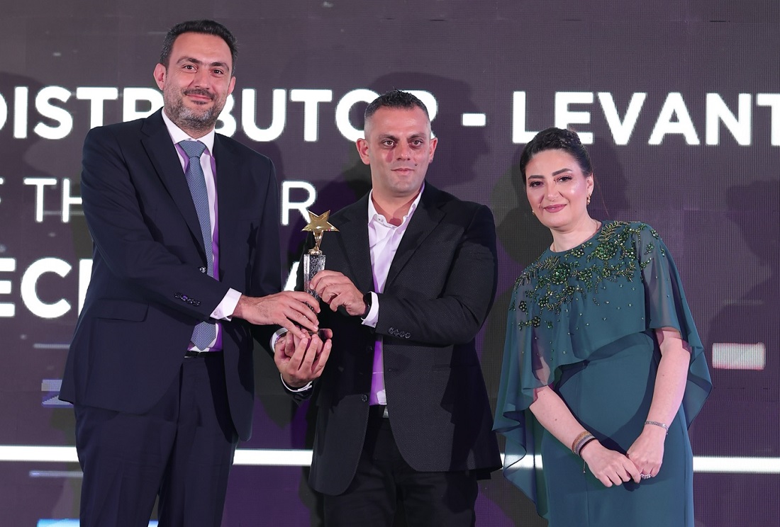 three people on a presentation stage as a trophy is handed over