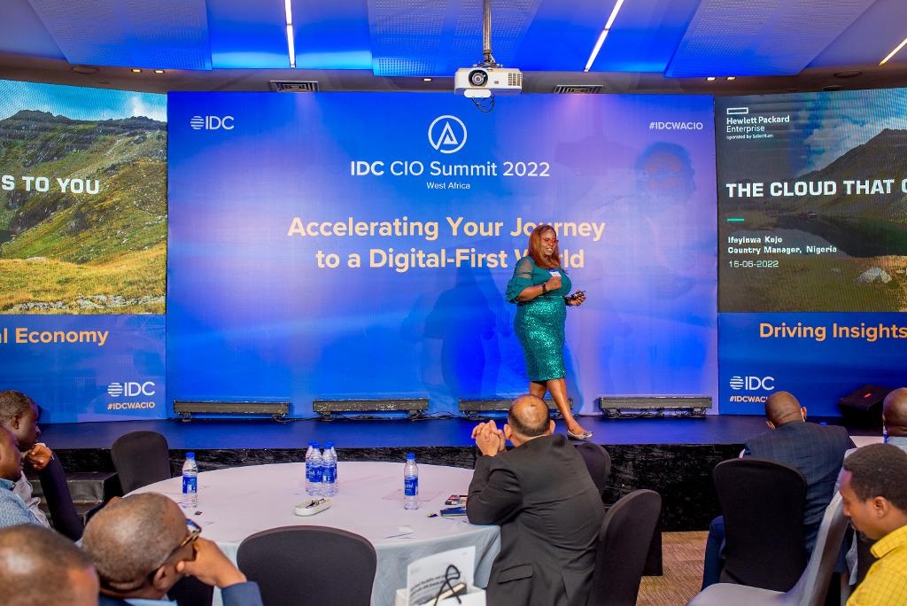 a woman is on stage making a presentation against a blue background