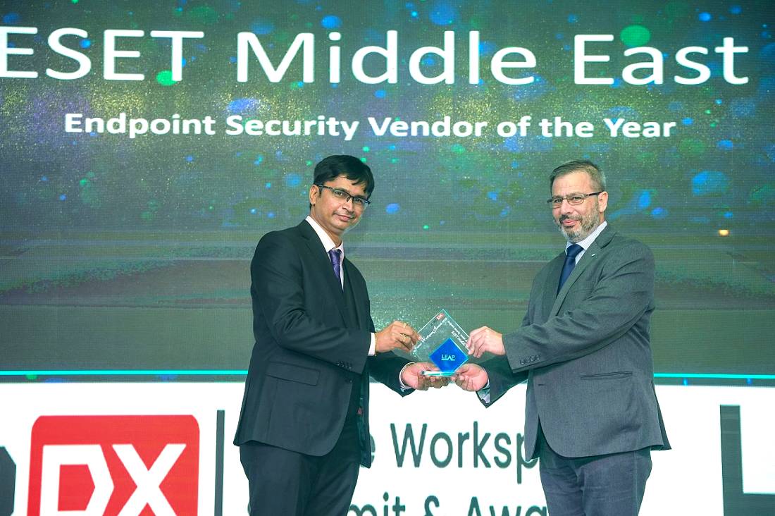 two men are seen on a presentation stage, one hands a trophy to the other