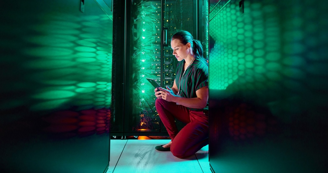 une femme vue dans un centre de serveurs avec des reflets de lumière verte tout autour