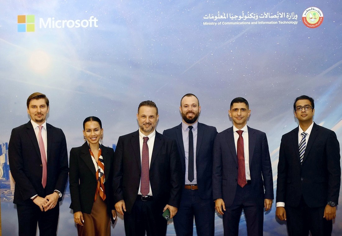 six personnes dans une photo de groupe avec le logo Microsoft en arrière-plan