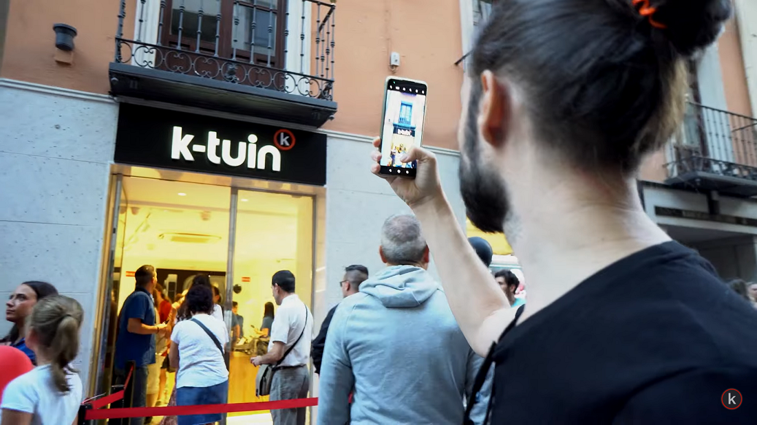 un homme tient un smartphone et prend la photo d’une devanture de magasin