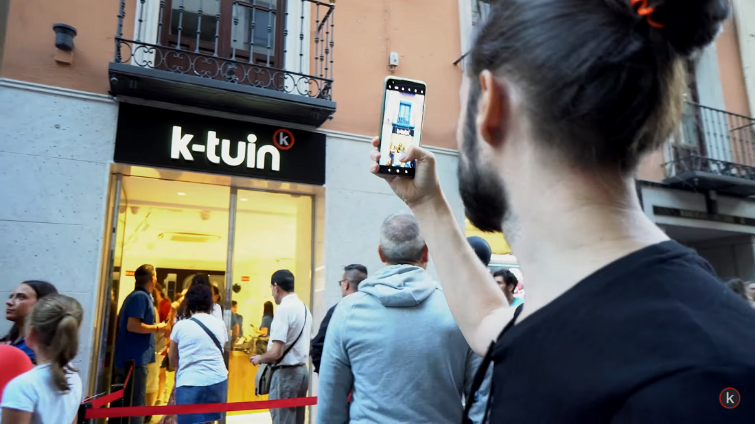 man holds a smartphone and photographs a shop front