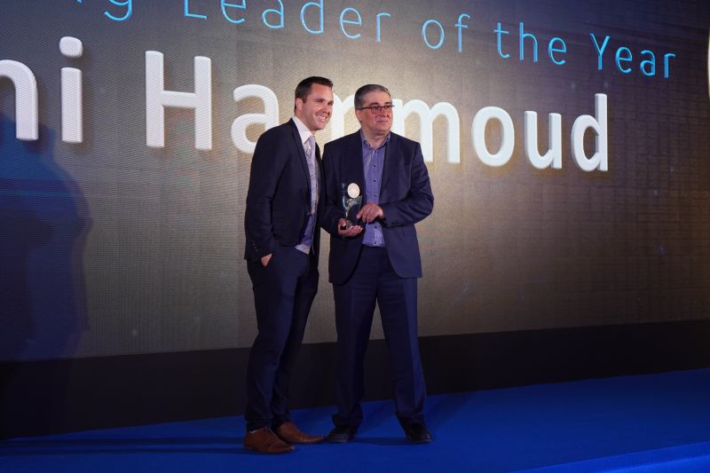 two men on stage with one handing a trophy to the other