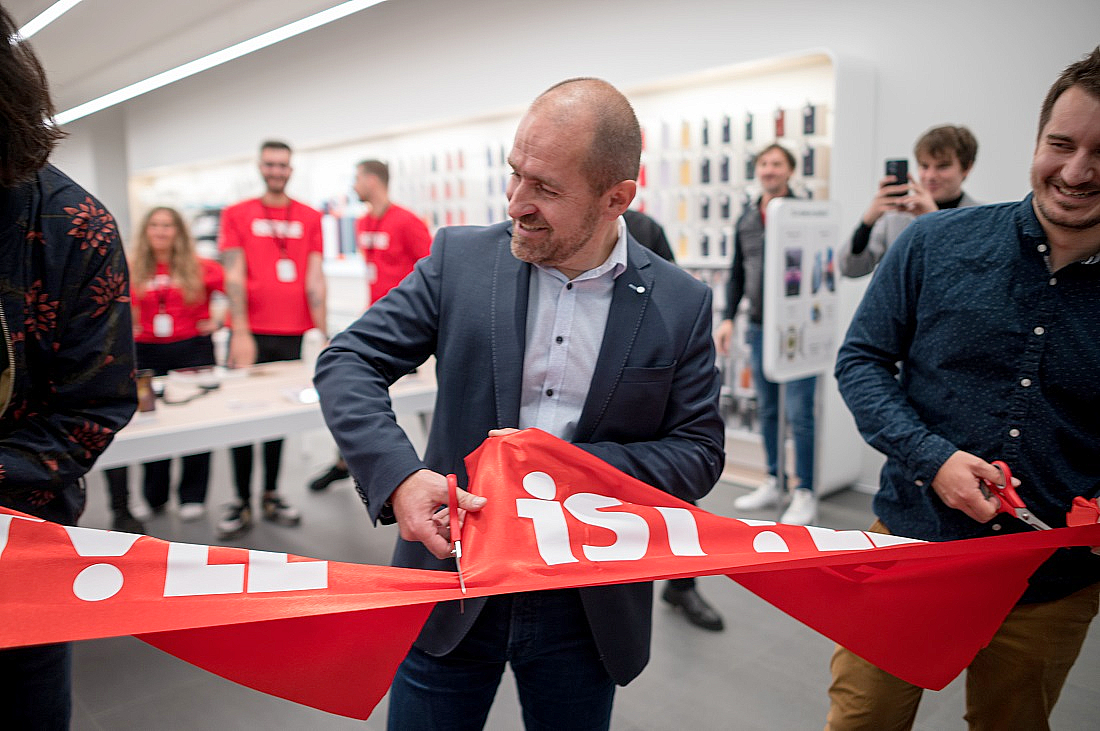 three men are seen with one of them using scissors to cut through a red banner