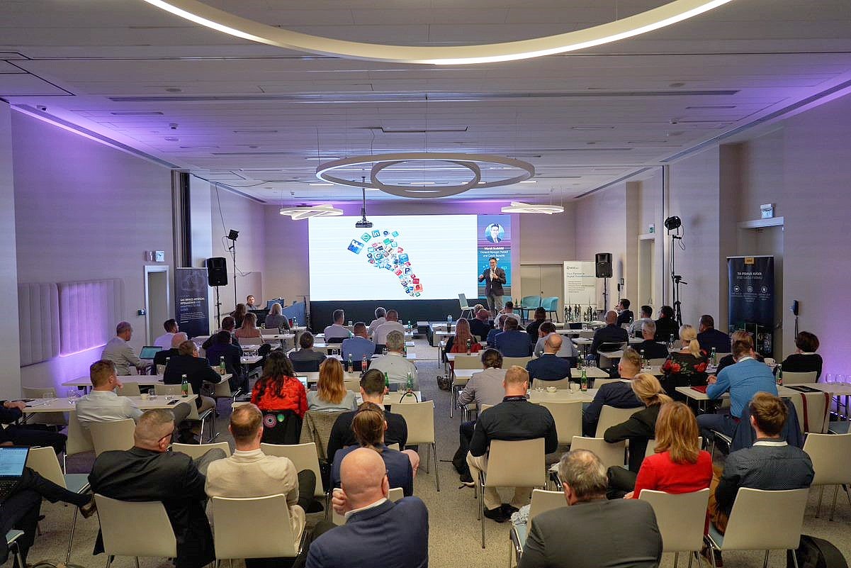 a room full of people are sitting and watching a presentation from a man standing at the front of the room