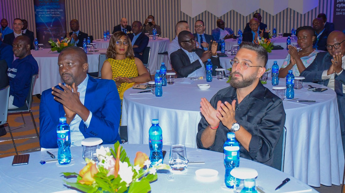 two people sitting at a table at an event are seen clapping a presentation