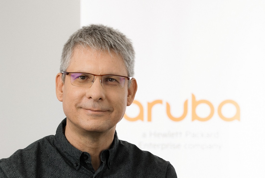 un homme portant des lunettes est vu souriant dans une pose de la tête et des épaules