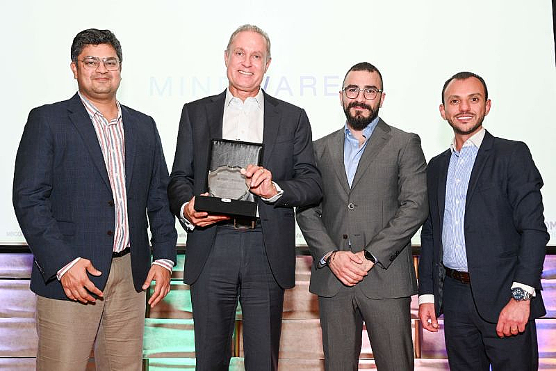 four men are seen at a presentation, with the man on second left holding a trophy