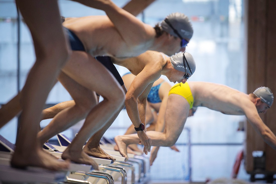 a group of people are diving into a swimming pool seen from the side