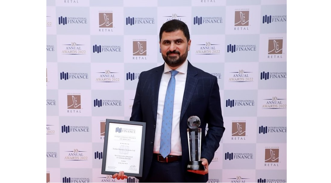 a man is seen holding a certificate and a trophy against a logo covered backdrop