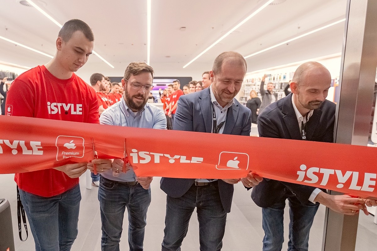 quatre hommes coupent un gros ruban rouge tendu sur le devant d'un magasin de haute technologie