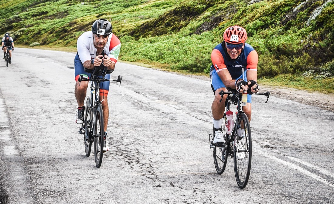 two men on racing bikes climb a hill