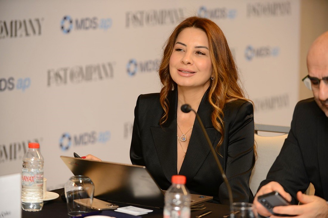 a woman in a business suit presents at a desk