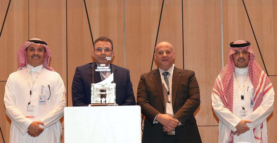 Four men on a presentation stage with a trophy in front of them