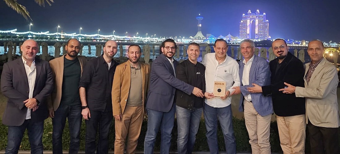 A group of men are holding an award trophy with a night landscape behind them